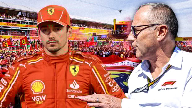Stefano Domenicali and Charles Leclerc look at one another in front of a Ferrari background