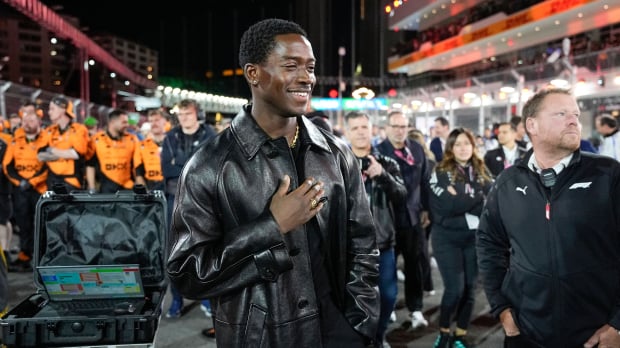 Damson Idris in sleek all black outfit with hand his hand on his chest on the F1 Las Vegas GP grid