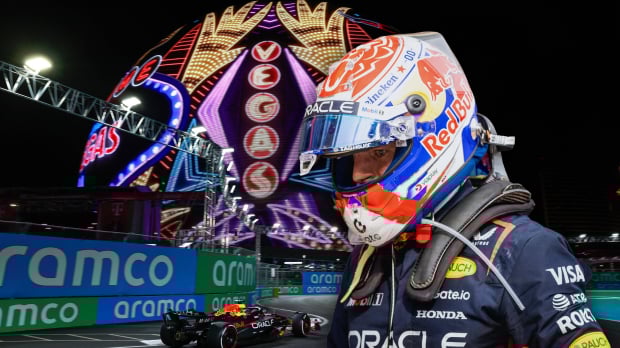 Verstappen in his race suit and helmet edited in front of a picture of a Red Bull car on the Vegas track below the sphere at night