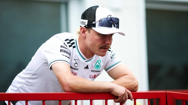 Bottas in an official Mercedes F1 team t-shirt, slumped over a railing in the F1 paddock looking despondent