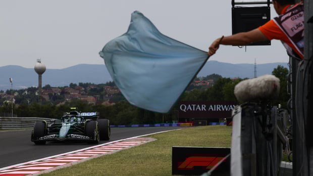 A marshall waves a blue flag at the 2024 Hungarian Grand Prix trackside