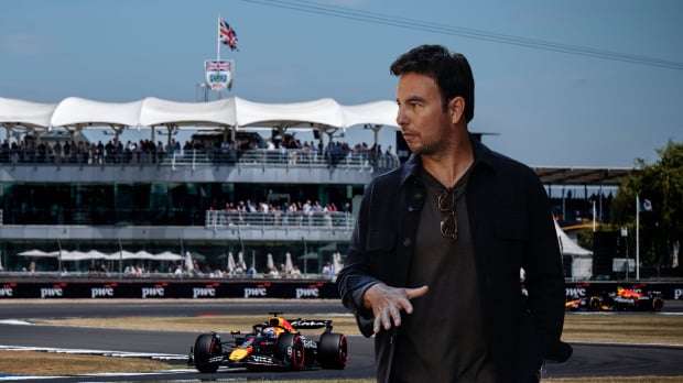 Sergio Perez in front of the Silverstone track as two Red Bulls drive behind him