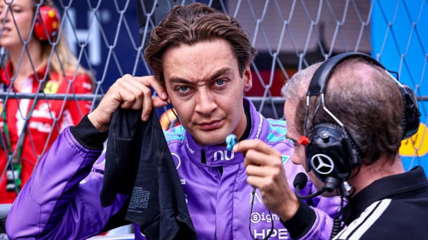 Russell screwing up his face on the F1 grid at Miami in bright purple race suit — Photo: © IMAGO