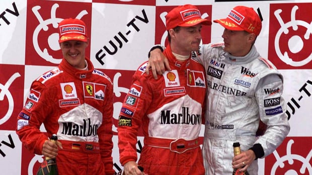 Mika Hakkinen consoles Eddie Irvine after winning the 1999 title as a happy Michael Schumacher looks on