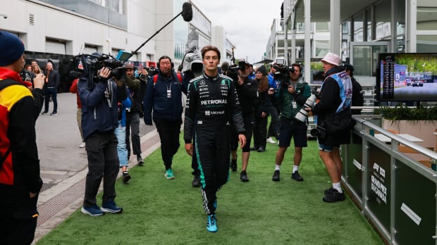 George Russell walks down the paddock surrounded by photographers after retiring from the Canadian Grand Prix — Photo: © IMAGO