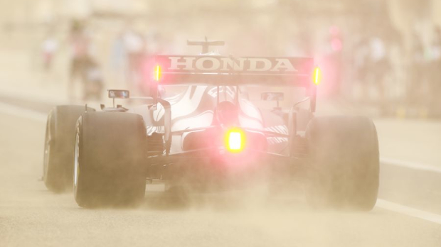 The AlphaTauri of Yuki Tsunoda is barely visible in the sand.