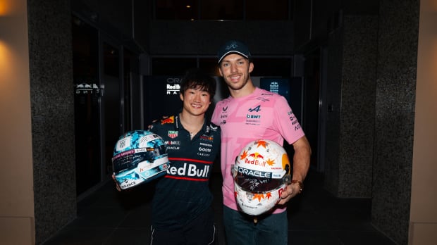 Yuki Tsunoda and Pierre Gasly smiling at the camera after their helmet swap at the Abu Dhabi Grand Prix 2025
