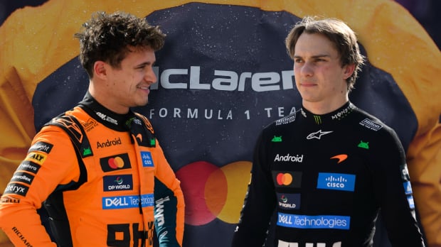 Lando Norris and Oscar Piastri look at each other with a McLaren logo background