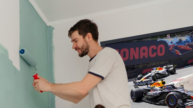 A man painting his wall as the Monaco Grand Prix fades in the background