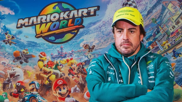 Mario Kart world background with Alonso sat crossed legged and with arms crossed looking grumpy in Aston Martin kit — Photo: © IMAGO