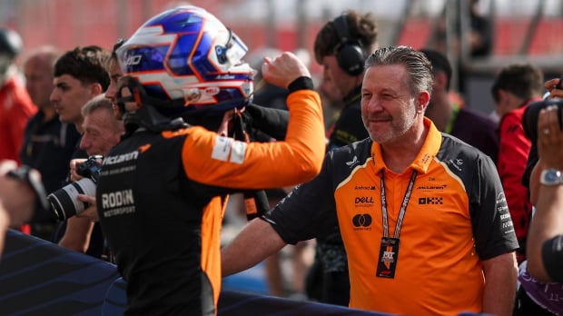 Dunne facing away from the camera towards McLaren boss Brown in the paddock
