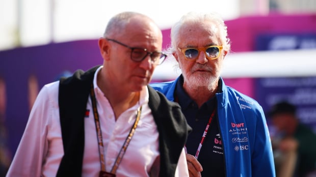 Domenicali closest to camera but out of focus in white shirt walking next to Briatore in blue and pink Alpine kit — Photo: © IMAGO