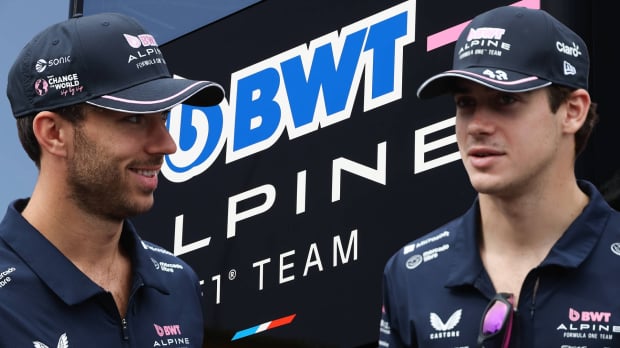 Pierre Gasly and Franco Colapinto look at each other to the background of an Alpine logo