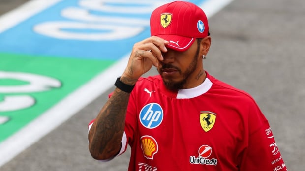 Hamilton dipping his Ferrari cap sombrely, partially hiding his face