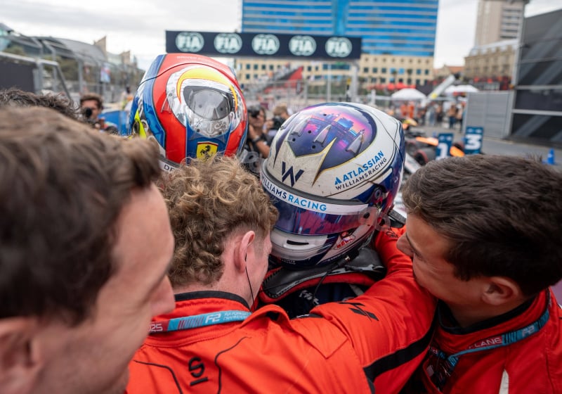 Williams junior Luke Browning wearing his race helmet and celebrating with his team after a race