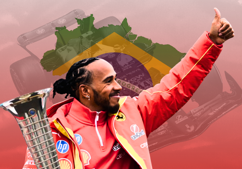 Lewis Hamilton waves and smiles as he holds a trophy with the brazil flag in the background