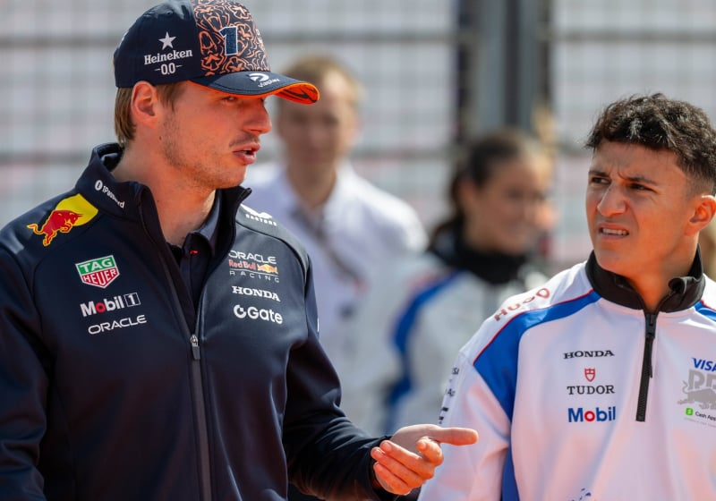Verstappen and Hadjar mid-discussion on a paddock walk