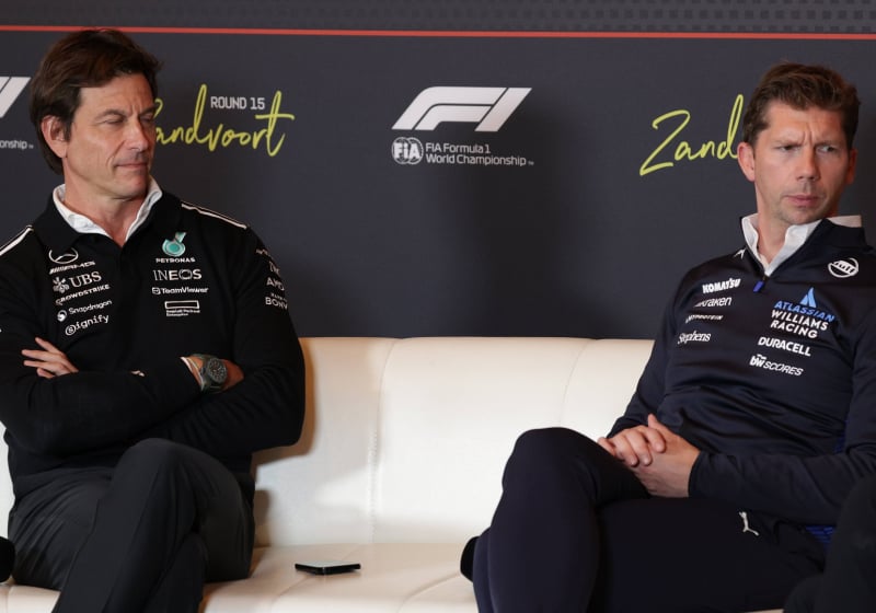 Wolff looking at Vowles with pride as Vowles looks away, both sat next to each other on the FIA press conference sofa
