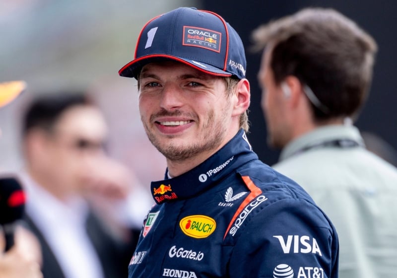 Max Verstappen smiling at the camera in Red Bull F1 team kit