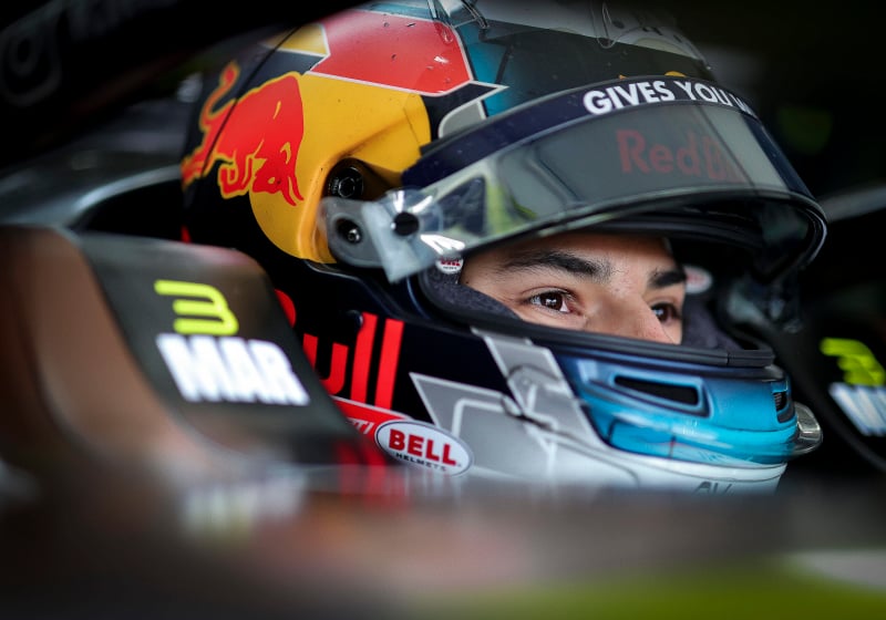 Pepe Marti sits in his Formula E car with his Red Bull-inspired helmet on