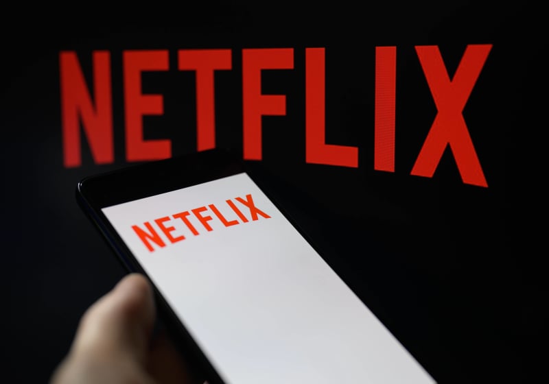 Netflix logo on TV, with smartphone displaying the same logo next to it