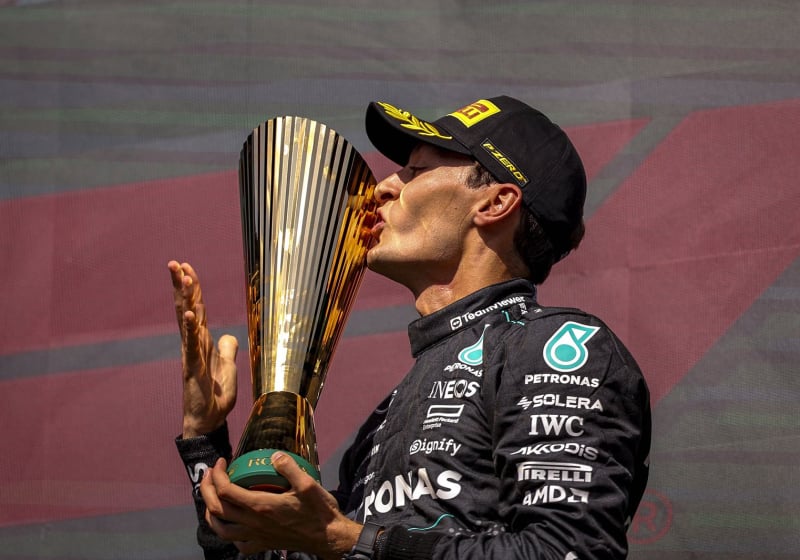 George Russell kisses a trophy on the F1 podium