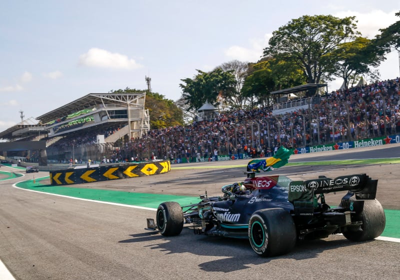 Lewis Hamilton waves a Brazil flag as he celebrates at the Brazilian Grand Prix