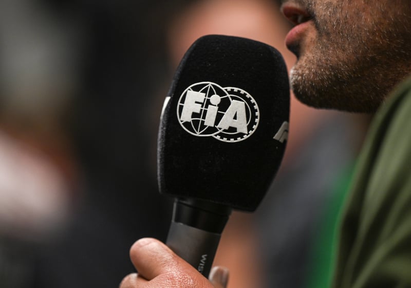 An interviewer holds an FIA microphone