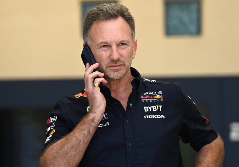 Horner in Red Bull kit looking down at his phone