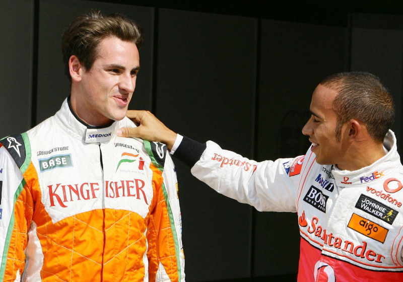 Sutil and Hamilton in 2009. Both in race suits and Sutil smiling while Hamilton rests his hand on Sutil's shoulder. 