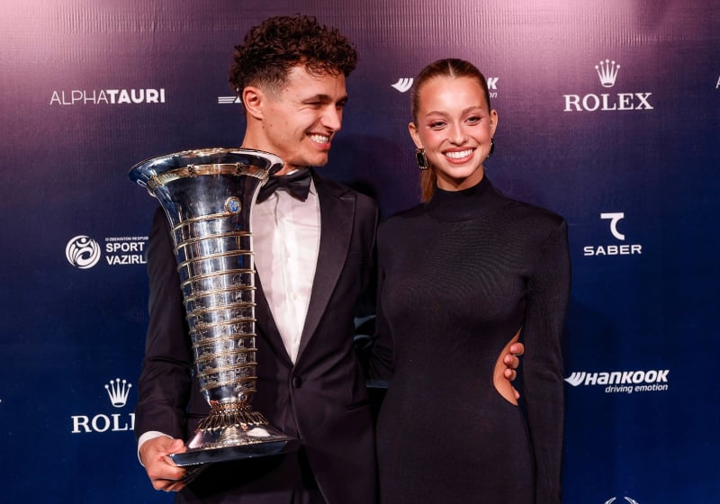 Lando Norris holding F1 drivers' trophy alongside Magui Corceiro at 2025 FIA prize ceremony