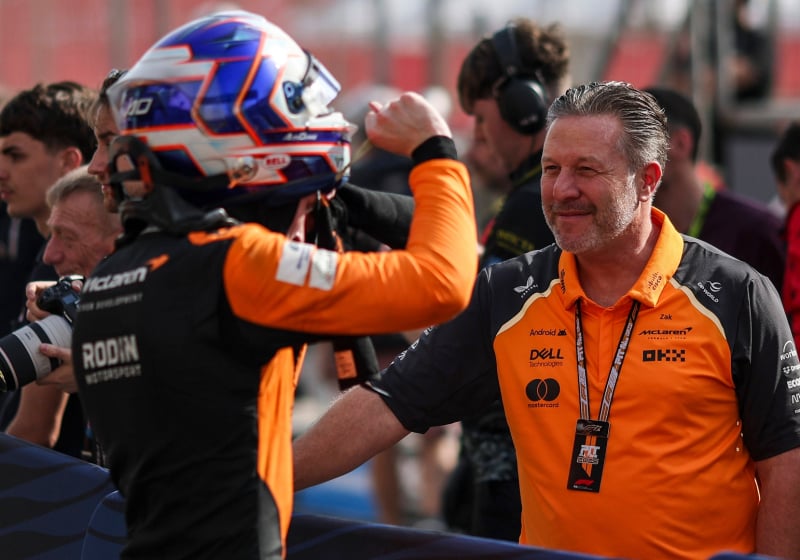Dunne facing away from the camera towards McLaren boss Brown in the paddock