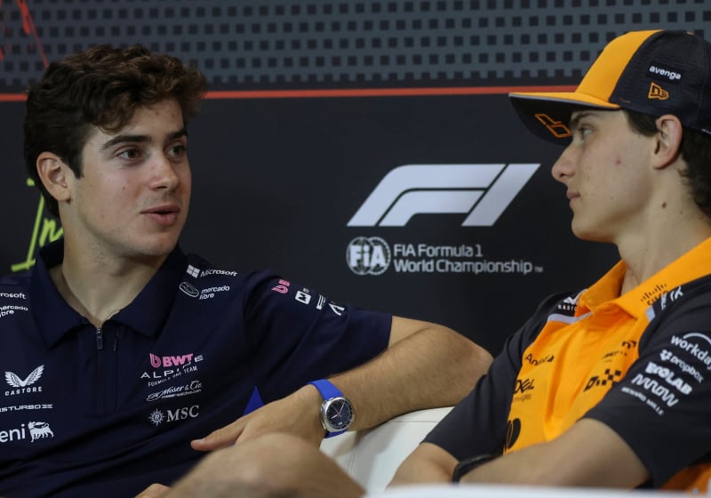 Colapinto and Piastri facing each other in conversation on the FIA press conference couch