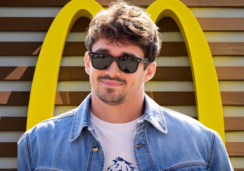 Charles Leclerc smiles with the McDonalds logo behind him