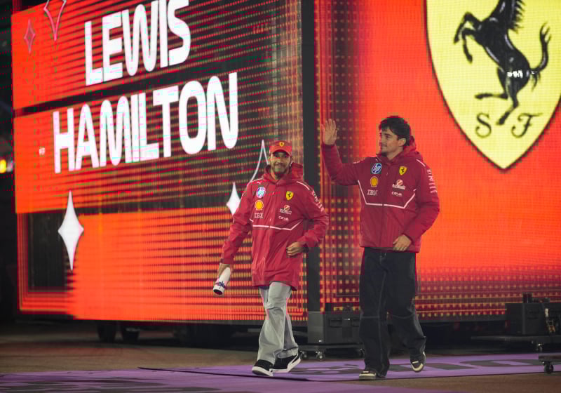Lewis Hamilton and Charles Leclerc walk with a Ferrari background