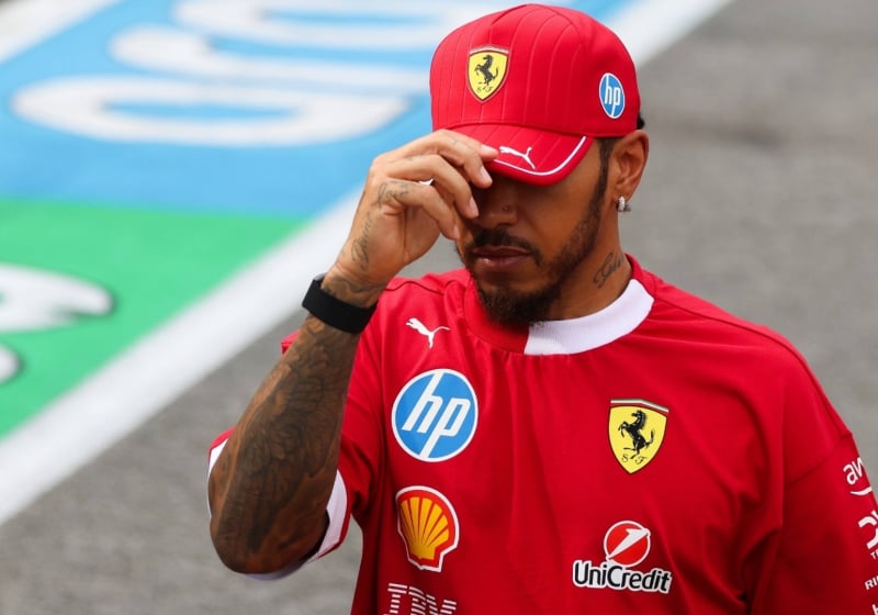 Hamilton dipping his Ferrari cap sombrely, partially hiding his face